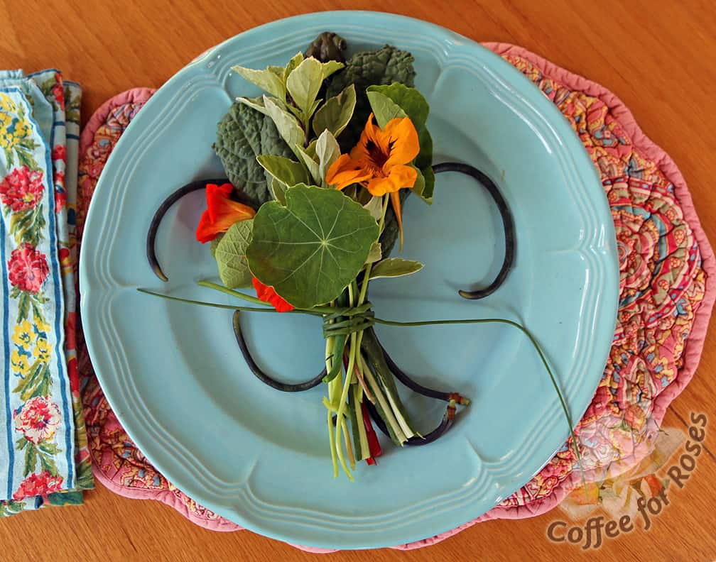 This edible bouquet is made from nasturtiums, kale, chard, variegated basil, green beans and red noodle beans. Tied with two chives.