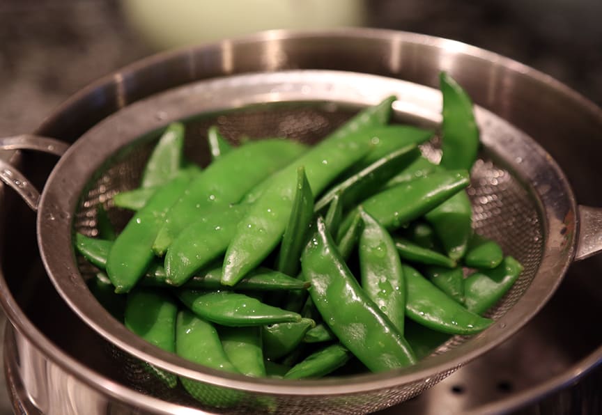 The snow peas get steamed for just one minute. Put them in the steamer once the water is already boiling and put the lid on the pot. Stir after thirty seconds and replace lid. The peas should be bright green but still crunchy. Pour them into a colander or sieve and immediately run cold water over them to stop their cooking. 