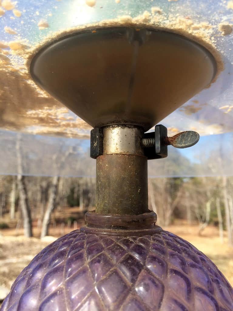 This shows the clamp that holds the feeder on the pole. The decorative copper pole stops just below the clamp. A hose clamp holds the lampshade in place and another clamp holds up the lower guard.