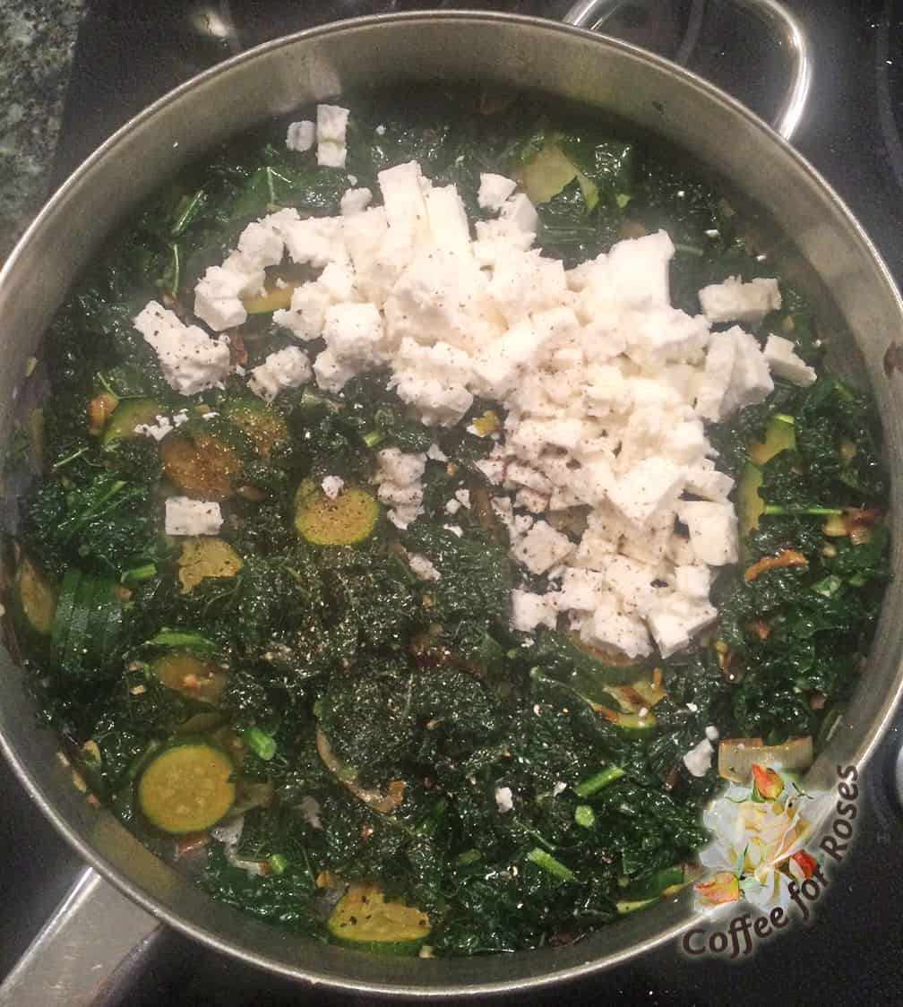 After the veggies are wilted, add the garlic and the feta cheese and stir to mix them together.