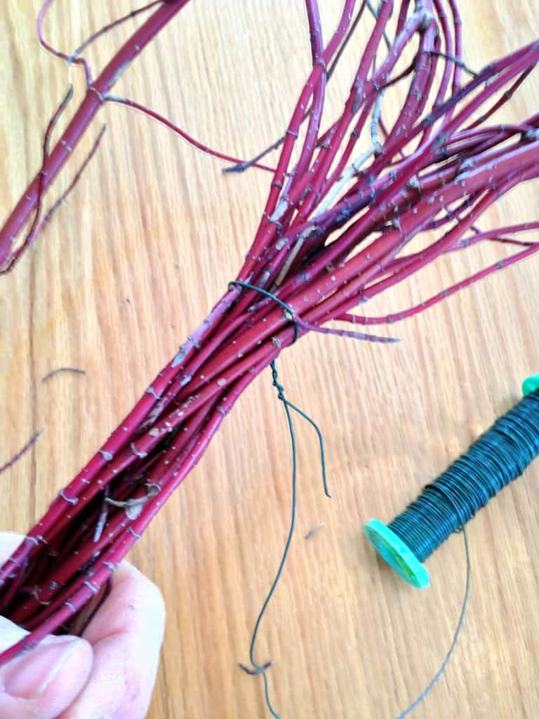 Wrap the wire around the bundle you're holding, but don't cut the wire off of the spool just yet.