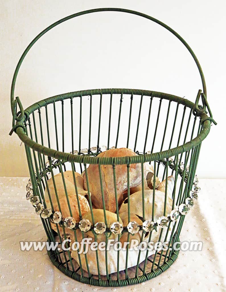 This basket was painted green. Next I attached a length of chandelier chain to the middle. Last year this basket was in the garden, filled with broken shells.