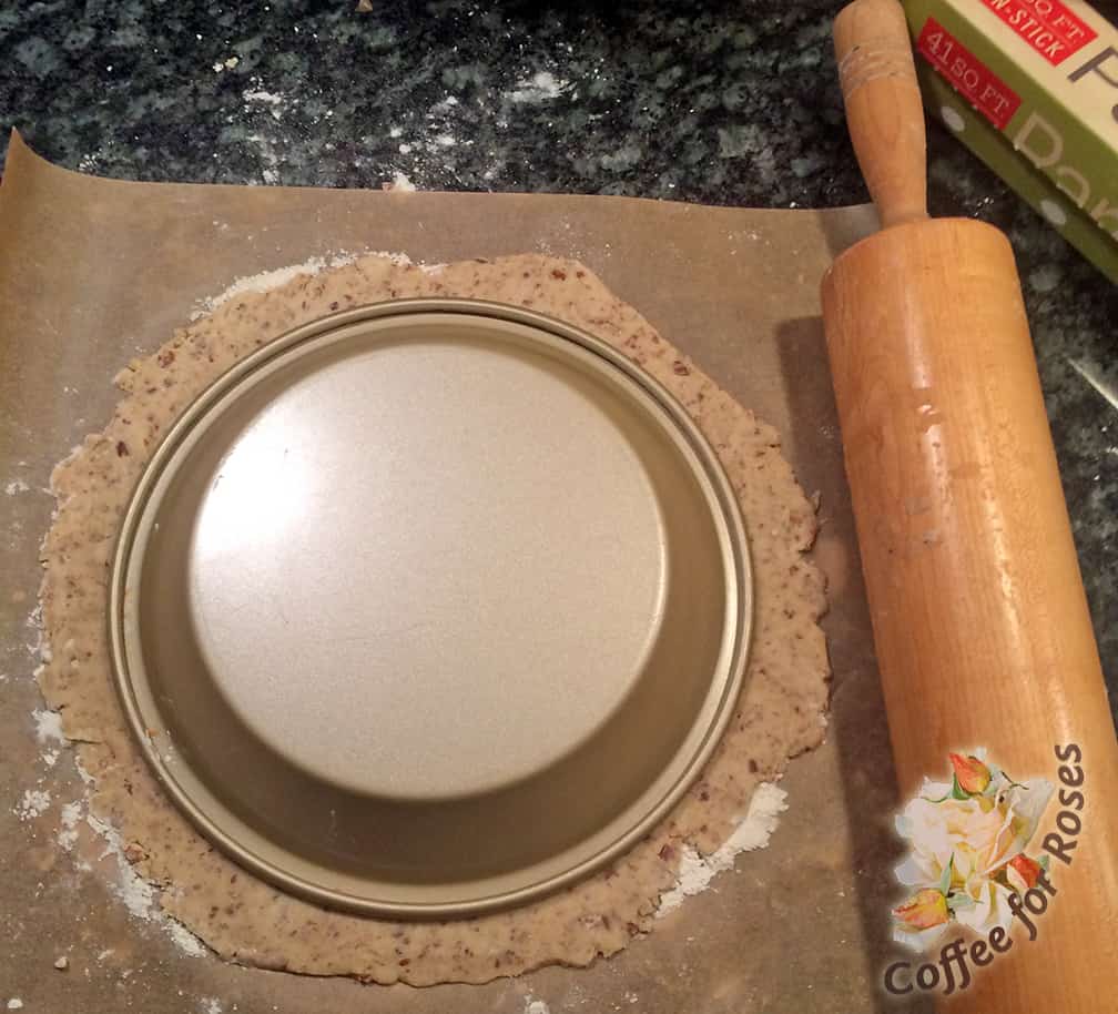 Rolling the dough out on a piece of parchment paper makes it easy to transfer to the pie tin. Dust the paper with flour, roll out the dough (dusting the top with flour so that the rolling pin doesn't stick) until the dough circle is just over an inch wider than your pie tin. Put the tin on top of the dough as pictured. 