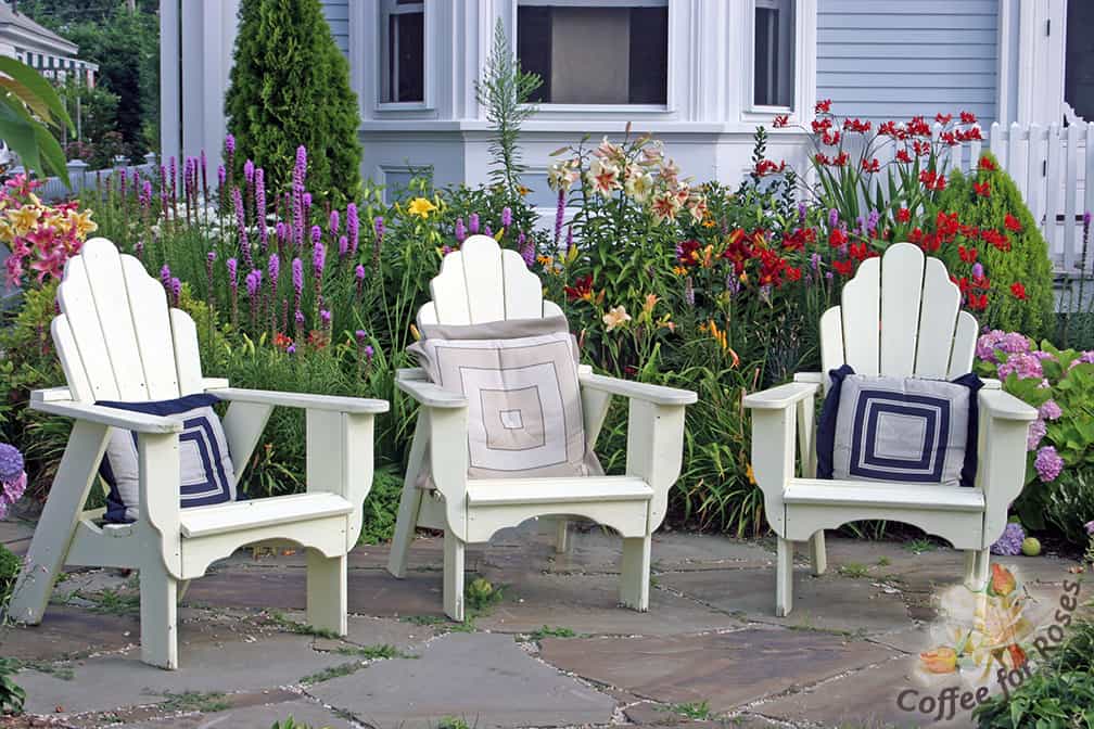 This front yard garden not only contains a variety of perennials and a couple of shrubs, but a small patio area and chairs as well. 