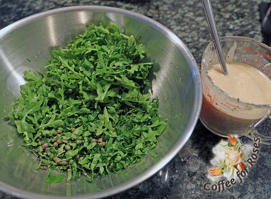 Chop all the herbs finely and slice the arugula into ribbons. Beat together the dressing ingredients in a large measuring cup or small bowl and pour that over the cooled potatoes. 